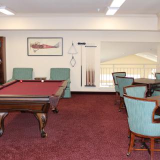 A cozy game room with a pool table and seating area on red carpet.