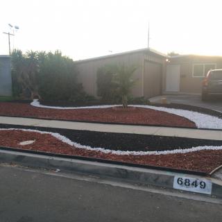 A modern xeriscape front yard with curved rock patterns and a minimalistic design.