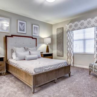 A stylishly decorated bedroom with a bed, nightstands, and a window with patterned curtains.
