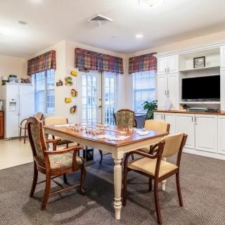 A cozy dining area with a wooden table and chairs, complete with a television and decorated windows.