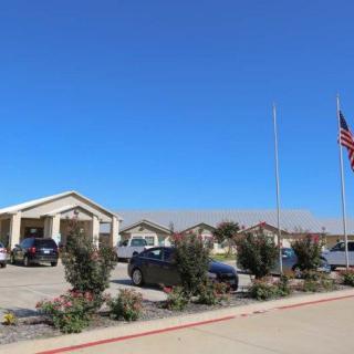 A building with a parking lot and cars, featuring an American flag on a clear day.