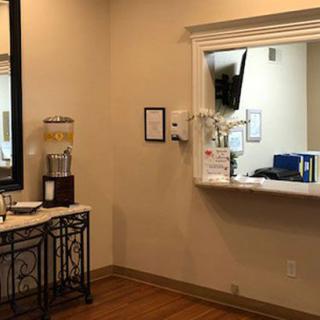 A view of a waiting room with a reception window and a water dispenser.