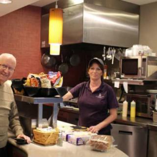A customer at a restaurant counter being served by an employee.