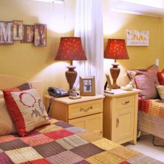 A cozy bedroom with quilted bedding, warm lighting from lamps, and a decorative nightstand.