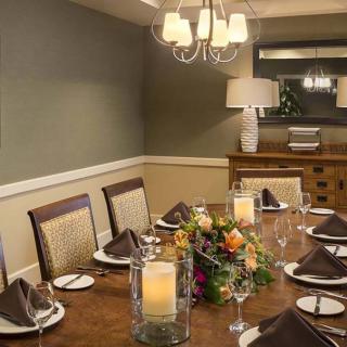 An elegantly set dining room table with a centerpiece of flowers and candles, under a stylish chandelier.