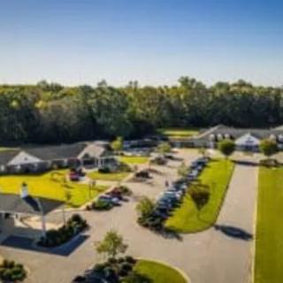 Aerial view of a facility with multiple buildings and a parking lot surrounded by greenery.