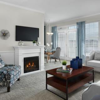 A modern living room with a cozy fireplace, stylish furniture, and large windows letting in natural light.