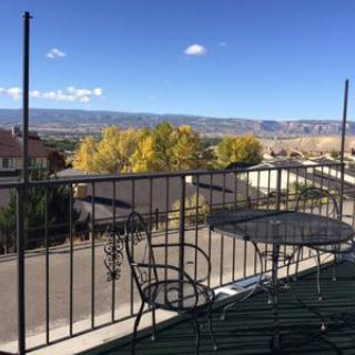 A scenic balcony overlooking a mountainous landscape under a clear blue sky.