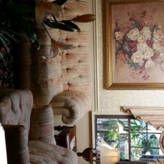 A cozy living room with plush furniture and a floral painting on the wall.