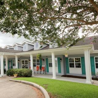 A single-story house with a covered porch and surrounding greenery.
