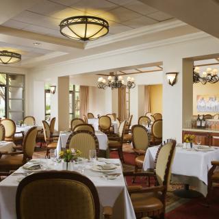 A well-lit, elegantly decorated restaurant dining room with neatly arranged tables and chairs.