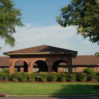 A well-maintained building surrounded by lush greenery and clear skies.