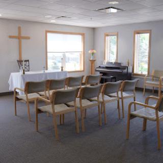 A serene chapel setting, featuring a cross and seating arranged for a service.