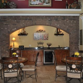 A cozy kitchen and dining area with a brick archway and wooden cabinetry.