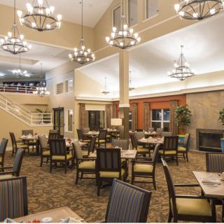 A spacious dining area with elegant chandeliers and neatly arranged tables and chairs.