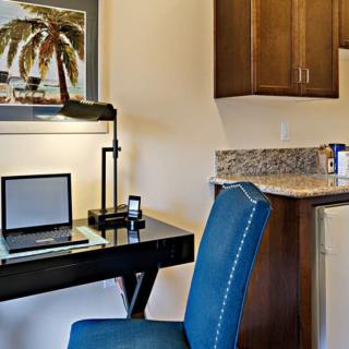 Modern workspace with a desk, laptop, and kitchenette.