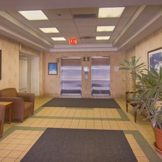 A lobby area with elevators, seating, and indoor plants.