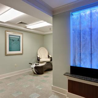 A serene spa interior featuring a relaxing chair and a calming water wall.