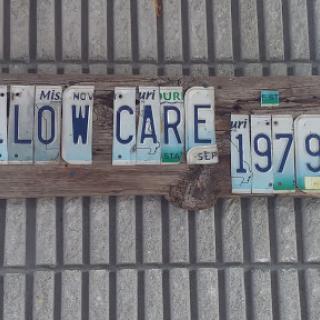 Creative wall art made from vintage license plates spelling 'LOW CARE' with the year '1979'.