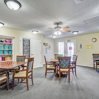 A well-lit dining area featuring multiple tables and chairs, with colorful shelving in the background.