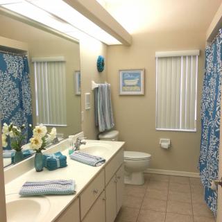 A neatly organized bathroom with blue accents and a large mirror.