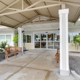 The welcoming entrance of a facility with outdoor seating and a protective canopy.