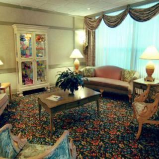 A classic-style living room featuring comfortable sofas, a center table, lamps, and a patterned carpet.