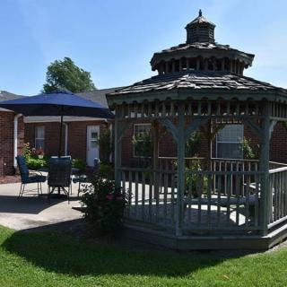 A tranquil backyard featuring a wooden gazebo and patio with an umbrella.