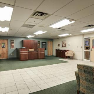 A spacious office lobby with a reception desk, comfortable seating, and a mix of tile and carpet flooring.