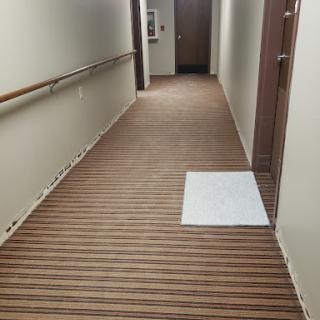 A clean and well-maintained hallway featuring wood-like flooring with a cleaning cloth positioned on the floor.