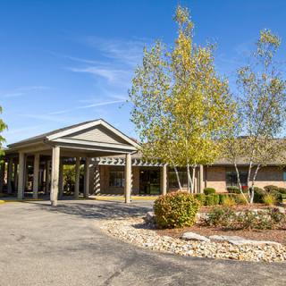 A building entrance surrounded by trees and landscaping under a clear blue sky.