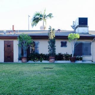 A small house with a well-maintained lawn and potted plants in the front yard.