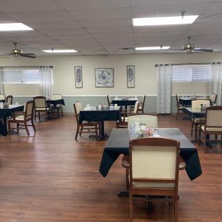 An empty dining room with neatly arranged tables and chairs on a wooden floor.