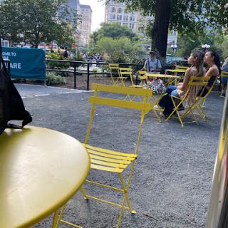 A serene park scene featuring yellow chairs and people enjoying the outdoors.
