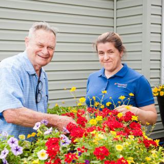 Two people enjoying gardening with vibrant flowers.