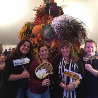 A group of friends enjoying an autumn event with colorful decorations and playful props.