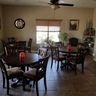 A cozy dining area with several tables and chairs, decorated with plants and wall art.