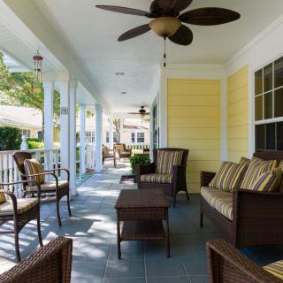 A spacious porch with comfortable seating and a ceiling fan, perfect for enjoying a sunny day.