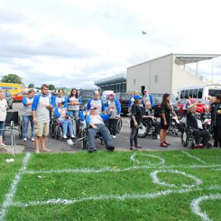 A lively outdoor event with a diverse crowd participating in various activities on a grassy field.
