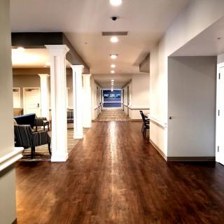 A well-lit hallway with wooden flooring and white columns.
