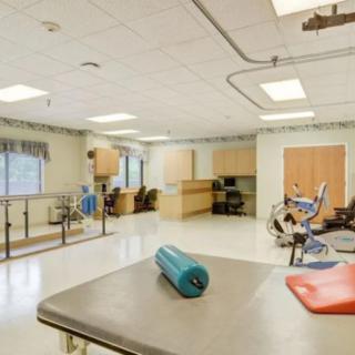 A clean and well-equipped physical therapy room with exercise equipment and workstations.