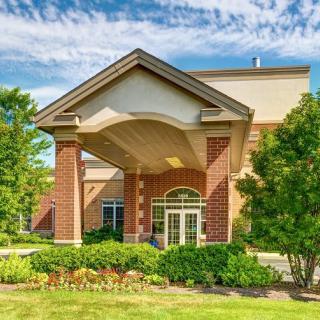 A brick building entrance with columns and well-maintained landscaping.