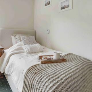 A cozy and minimalist bedroom featuring a neatly made bed, simple decor, and a touch of elegance.