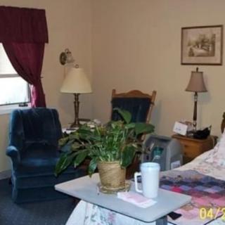 Cozy room with a bed, chairs, and a plant on a side table.