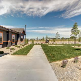 A serene outdoor space featuring a well-maintained pathway leading to a grassy area under a beautiful sky.