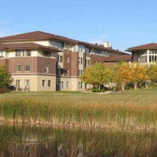 A modern building surrounded by trees and a pond, set in a tranquil landscape.