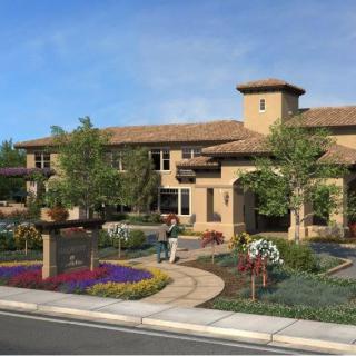 A residential building with well-maintained landscaping, featuring a garden, trees, and flowers.