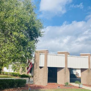 A serene view of a building surrounded by greenery under a partly cloudy sky.