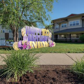 A colorful welcome sign in front of a residential community on a sunny day.