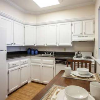 A modern kitchen with white cabinets and a small dining area.